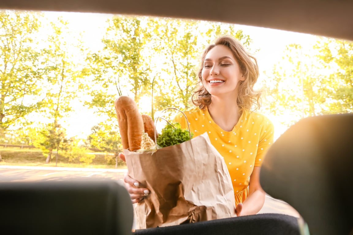 Young Woman Putting Grocery Bag in Car